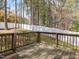 A wooden back deck overlooks a spacious backyard surrounded by tall trees and a white privacy fence at 5 Maidenhair Ct, Durham, NC 27703