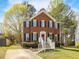 Charming two-story brick home with well-maintained lawn and inviting white railed front porch and mature trees at 5 Maidenhair Ct, Durham, NC 27703