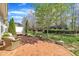 Beautiful brick patio with wicker furniture, lush landscaping, and a tree canopy overhead at 5033 Homeplace Dr, Apex, NC 27539