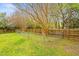 Spacious backyard featuring lush grass, trees, and a partially fenced in area at 516 Edinburgh Dr, Burlington, NC 27215