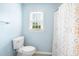 Well-lit bathroom with blue walls, a patterned shower curtain, and a toilet at 516 Edinburgh Dr, Burlington, NC 27215