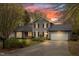 Charming two-story home with gray siding, black shutters, attached garage and landscaped front yard at sunset at 516 Edinburgh Dr, Burlington, NC 27215