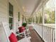 Cozy front porch featuring rocking chairs with red pillows, plants, and a view of the surrounding nature at 5209 Rivington Rd, Fuquay Varina, NC 27526