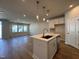 Open-concept kitchen with island, stainless appliances, and hardwood floors open to large living area at 609 Callan View Ave, Wake Forest, NC 27587