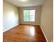 Cozy bedroom with large window, hardwood floors, and neutral paint at 6705 Somerknoll Dr, Durham, NC 27713