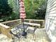 Wooden deck with a seating area shaded by a striped umbrella, perfect for outdoor relaxation at 6705 Somerknoll Dr, Durham, NC 27713