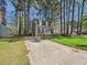 Quaint home with a long driveway and lush lawn, surrounded by tall trees and a tidy landscape at 7117 Sandringham Dr, Raleigh, NC 27613