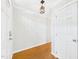 Clean hallway featuring hardwood floors, white walls, and stylish light fixtures near entry door at 7117 Sandringham Dr, Raleigh, NC 27613