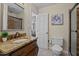 Bathroom featuring a granite-topped vanity, decorative mirror, walk-in shower, and a view into an adjacent room at 7317 Mill Ridge Rd, Raleigh, NC 27613
