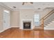 Bright living room showcasing a fireplace, staircase and hardwood flooring and a large window at 7819 Acc Blvd, Raleigh, NC 27612