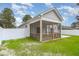 Rear exterior view of the home with a screened-in porch, manicured lawn, and white picket fence providing privacy at 8 Nottingham Pl, Smithfield, NC 27577