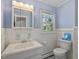 Powder blue bathroom with white ceramic tile, window, sink, toilet, and walk-in shower at 806 S First St, Smithfield, NC 27577