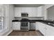 Kitchen featuring stainless steel appliances, white cabinets, and dark granite countertops at 8700 Leeds Forest Ln, Raleigh, NC 27615