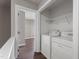 Bright laundry area featuring white washer and dryer, wire shelving, and hardwood flooring throughout at 8700 Leeds Forest Ln, Raleigh, NC 27615