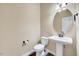 Half bathroom with tile flooring, pedestal sink, toilet, and a large round mirror at 8932 Buffalo Gourd Ln, Angier, NC 27501