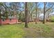 Large backyard with mature trees, green grass, and outbuilding with a deck at 927 Ferncrest Dr, Durham, NC 27705