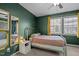 Bedroom with dark green walls, a bed, a gold trimmed mirror, and a window at 103 Friar Ln, Carrboro, NC 27510