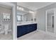 Bathroom vanity with double sinks, navy blue cabinets and large mirror, with adjacent toilet and linen cabinet at 1160 Duke Farm Dr, Wake Forest, NC 27587