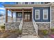 Inviting covered front porch with swing, wood ceiling, and stone steps leading to a charming double-door entrance at 1160 Duke Farm Dr, Wake Forest, NC 27587
