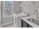 Bright laundry room with front load washer/dryer, white quartz counter, stainless sink and a view to the exterior at 1160 Duke Farm Dr, Wake Forest, NC 27587