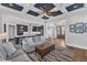 Open-concept living room featuring a coffered ceiling, hardwood floors, and seamless flow into the kitchen at 1160 Duke Farm Dr, Wake Forest, NC 27587