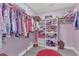 Organized walk-in closet with colorful clothing racks, shelving units and a pink round rug at 1160 Duke Farm Dr, Wake Forest, NC 27587