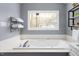 Bathroom with a soaking tub, quartz countertops, modern fixtures, and a large window with wooded views at 124 Holly Ridge Ln, Mebane, NC 27302