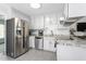 Clean white kitchen with stainless steel appliances, granite countertops, and light gray flooring at 124 Holly Ridge Ln, Mebane, NC 27302