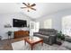 This living room features hardwood floors, a TV, a gray couch, and ample natural light at 124 Holly Ridge Ln, Mebane, NC 27302