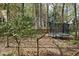 A spacious backyard featuring mature trees, a trampoline and a glimpse of the neighboring houses at 1550 Pathway Dr, Carrboro, NC 27510