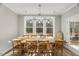 Sunlit dining area with a wooden table and woven chairs, showcasing a view of the outdoors through large windows at 201 W Amber Oak Drive, Selma, NC 27576