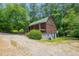 Charming log cabin with a covered porch and lush, mature trees surrounding the home at 207 High House Rd, Cary, NC 27513
