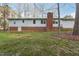 Back exterior view showcasing brick foundation, white siding, chimney and large yard at 209 High House Rd, Cary, NC 27513