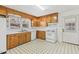 Bright kitchen featuring wood cabinets and white appliances with geometric flooring at 209 High House Rd, Cary, NC 27513