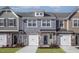 Charming townhome showcasing stone accents, individual garages, and appealing curb appeal with manicured landscaping at 2112 Willow Gln Dr, Graham, NC 27253