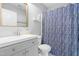 Well-lit bathroom featuring a white vanity, framed mirror, and a shower with a blue patterned curtain at 2400 Perennial St, Raleigh, NC 27603