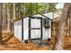 A shed with a ramp and black and white trim sits on a treed lot at 2400 Perennial St, Raleigh, NC 27603