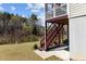 Backyard view of the house featuring a staircase and grassy yard with wooded area nearby at 2713 Tunstall Grove Dr, Apex, NC 27523
