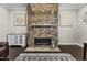Stone fireplace with mantle, flanked by wall art and decorative cabinet, adds cozy charm to the inviting living space at 2713 Tunstall Grove Dr, Apex, NC 27523