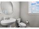 Bright half bath features modern fixtures with a pedestal sink, round mirror, and neutral wall color at 2713 Tunstall Grove Dr, Apex, NC 27523