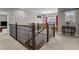 Second-floor hallway with an iron railing, leading to a sunny sitting room with bright yellow chairs at 2713 Tunstall Grove Dr, Apex, NC 27523