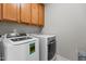 Laundry room showcasing a modern washer and dryer set with convenient overhead storage cabinets at 2713 Tunstall Grove Dr, Apex, NC 27523