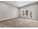 Spacious living room features neutral walls and plush carpeting, complemented by a bright window and glass door at 2713 Tunstall Grove Dr, Apex, NC 27523