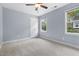 Bright bedroom featuring plush carpet, two windows for natural light, and a ceiling fan at 302 Rushingwater Dr, Cary, NC 27513