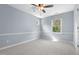 Cozy bedroom with neutral carpet, blue walls, large window, and a ceiling fan at 302 Rushingwater Dr, Cary, NC 27513