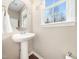 Cozy powder room with a pedestal sink, round mirror, and a window offering a view of the outdoors at 3690 Mabel Ln, Stem, NC 27581