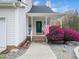 Charming home featuring a welcoming front porch adorned with an American flag and vibrant landscaping at 3690 Mabel Ln, Stem, NC 27581