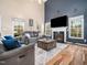 Inviting living room with a cozy fireplace, large windows, and comfortable gray sofas at 3690 Mabel Ln, Stem, NC 27581