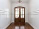 Elegant entryway with a double wooden door, gleaming hardwood floors, and classic wainscoting at 3908 Sage Ct, Wake Forest, NC 27587