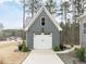 A detached one-car garage with white doors and concrete driveway surrounded by lush greenery at 3908 Sage Ct, Wake Forest, NC 27587